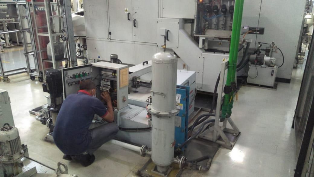 Technician servicing a control cabinet on the shop floor